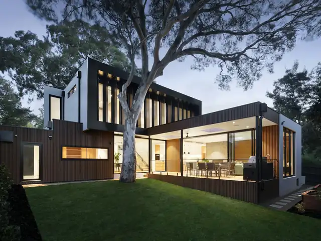 Modern house at dusk with a neat lawn under a large tree