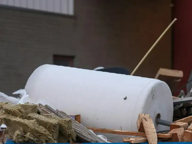 Skip filled with an old water tank, insulation and broken timber
