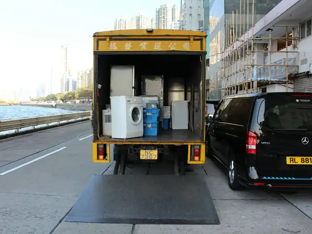 Box truck with its tail lift down, loaded with a washing machine and other appliances