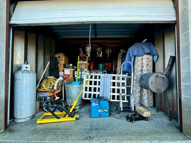 Open storage shed packed with tools, a gas cylinder and stored household items